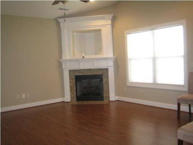 April 2012: the family room, empty and new-looking, with the corner fireplace and the original dark wood floor